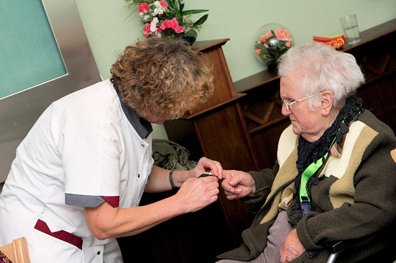 Eine ältere Person bekommt Unterstützung von einem Angehörigen in der häuslichen Pflege